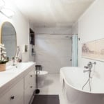 Modern bathroom with double vanity, free-standing bathtub, walk-in shower, and elegant decor, ideal for luxury living in Vancouver, BC. Features marble tiles, contemporary fixtures, and natural light.