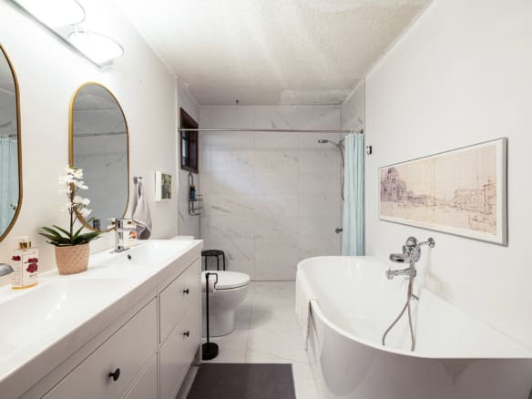 Modern bathroom with double vanity, free-standing bathtub, walk-in shower, and elegant decor, ideal for luxury living in Vancouver, BC. Features marble tiles, contemporary fixtures, and natural light.
