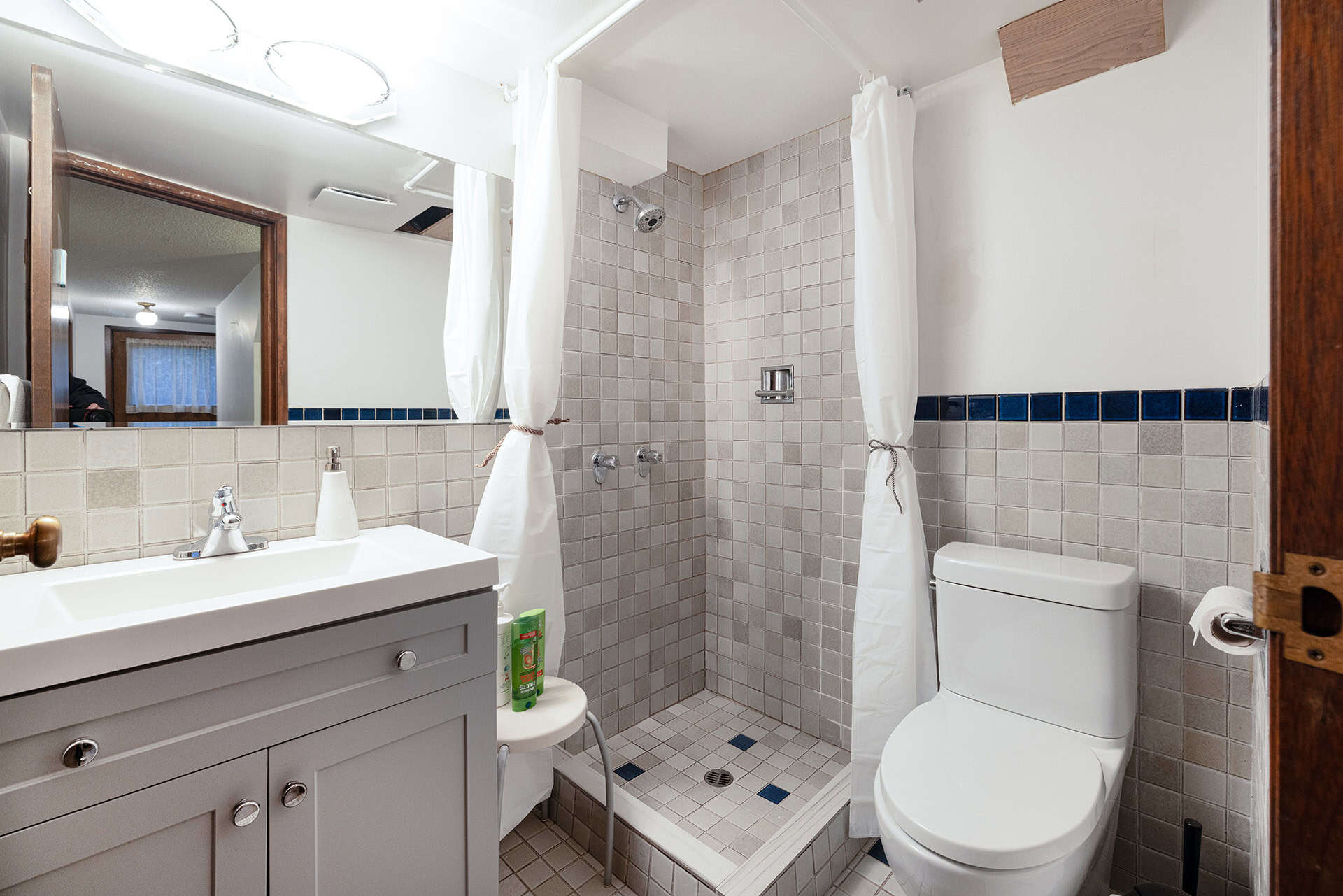 Modern bathroom with walk-in shower, white vanity, and toilet, featuring neutral tile accents and a cozy, functional design in Vancouver home.