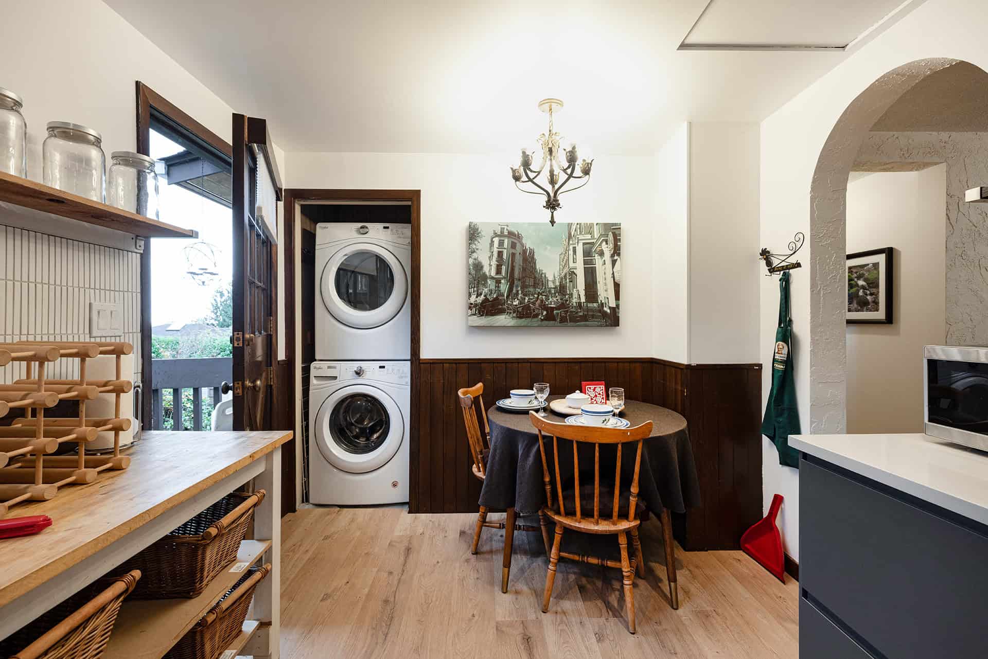 Cozy dining area with washer and dryer, wooden chairs, and wall art, in a bright, well-lit kitchen space showcasing Ontario real estate by Orca Realty Inc.