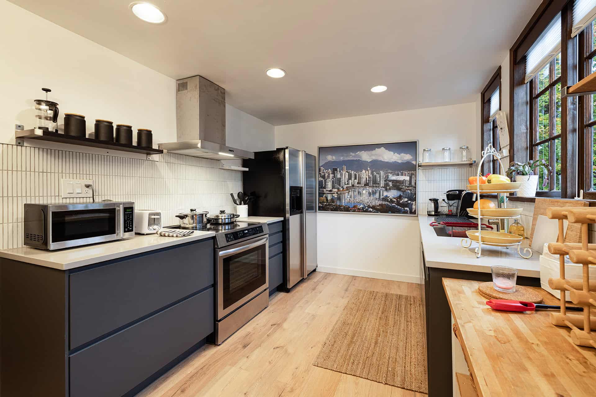 Modern kitchen with stainless steel appliances, wooden flooring, and large windows offering natural light and city views, perfect for Vancouver living.