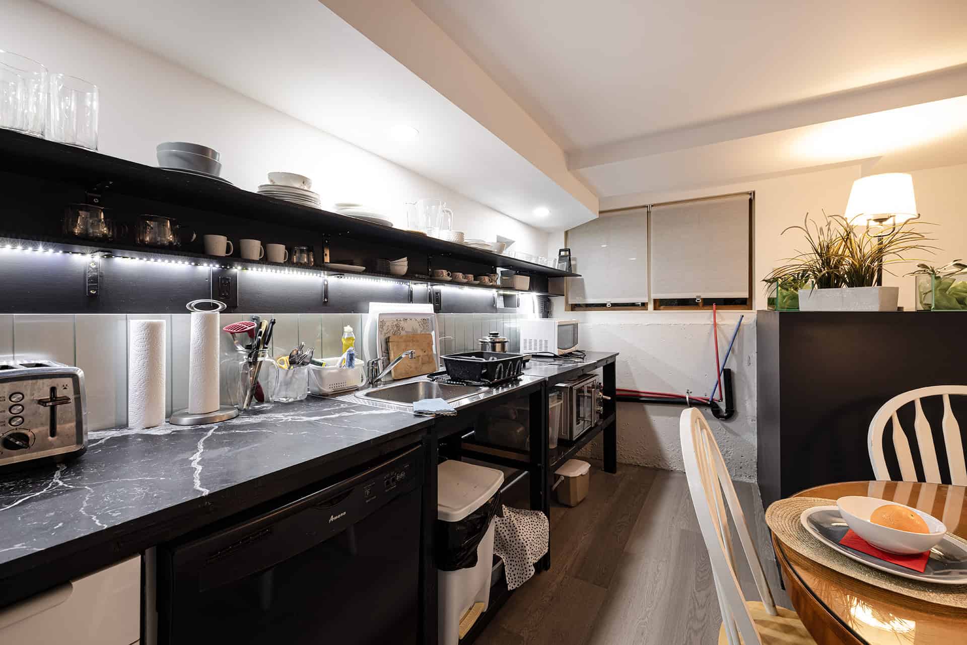 Modern kitchen with black marble countertops, open shelving, and contemporary appliances in a well-lit Vancouver home.
