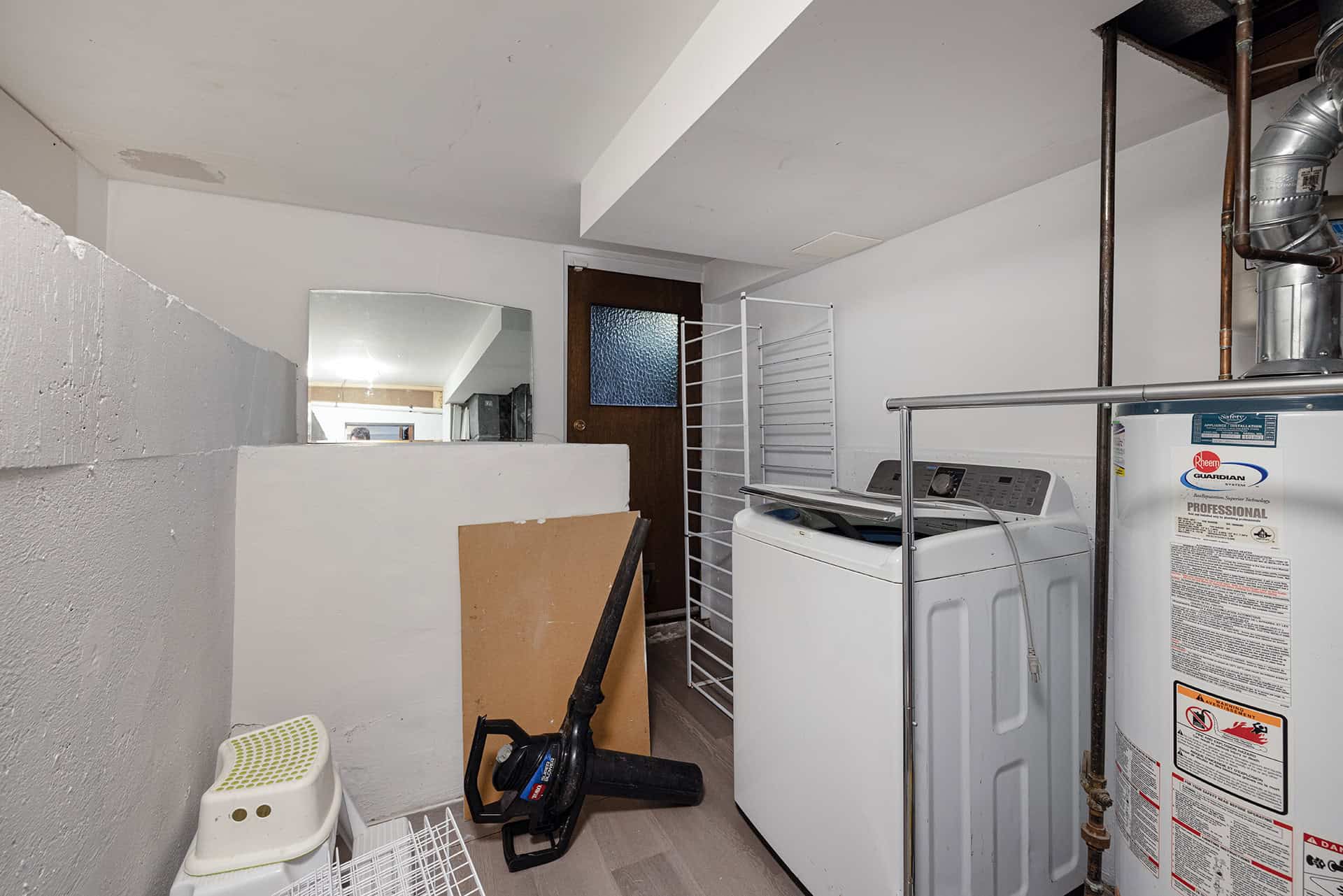Quiet laundry room with washer, water heater, and storage space, ideal for home convenience and utility needs.