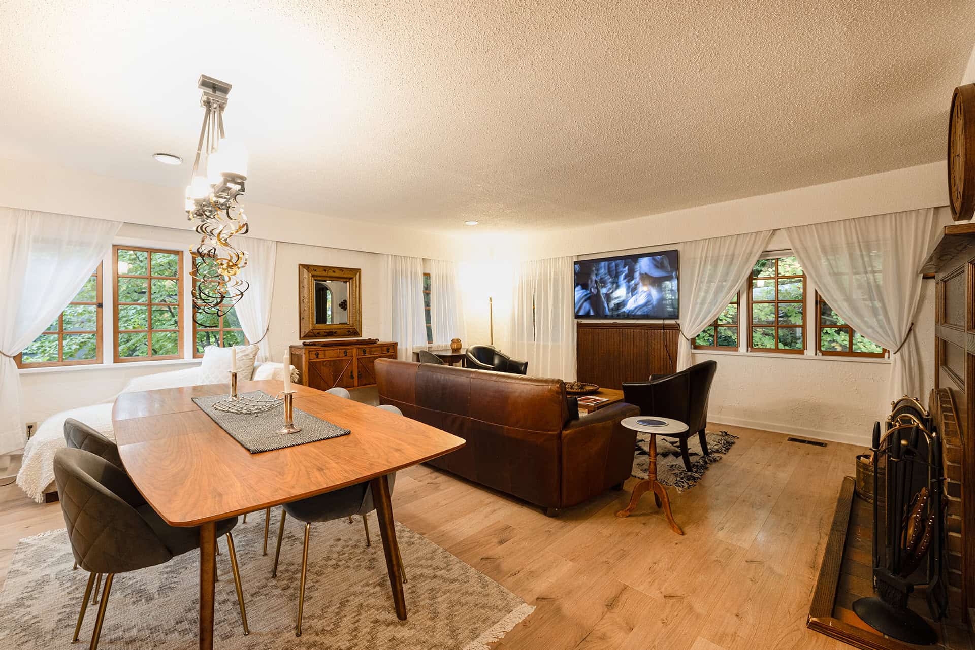 Comfortable living room with large windows, hardwood flooring, cozy fireplace, and modern TV setup, perfect for relaxing or entertaining in a family home or rental property.