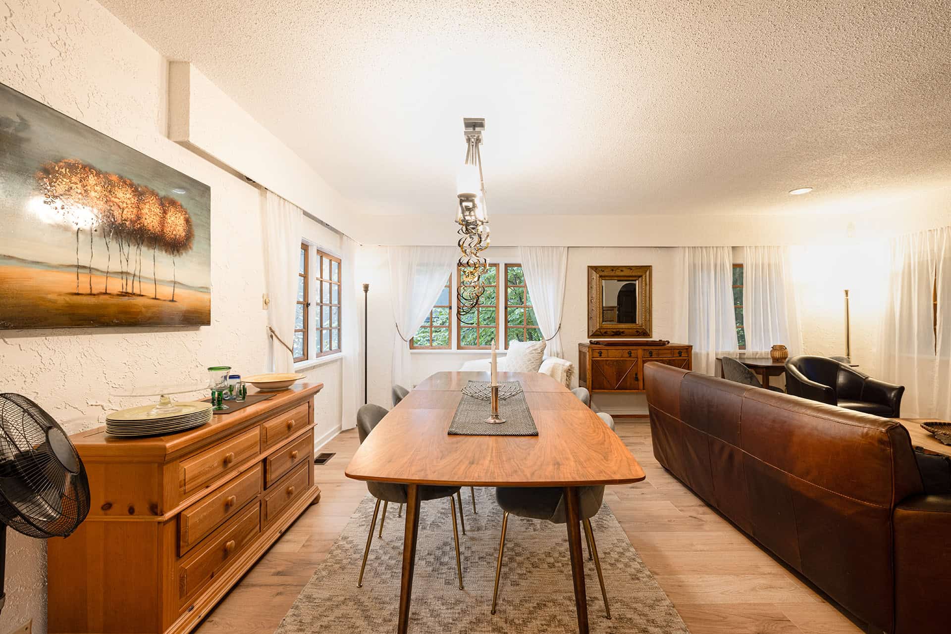 Spacious living and dining room with large windows, natural light, and cozy furniture in a home listed by Orca Realty Inc. in Victoria, BC.