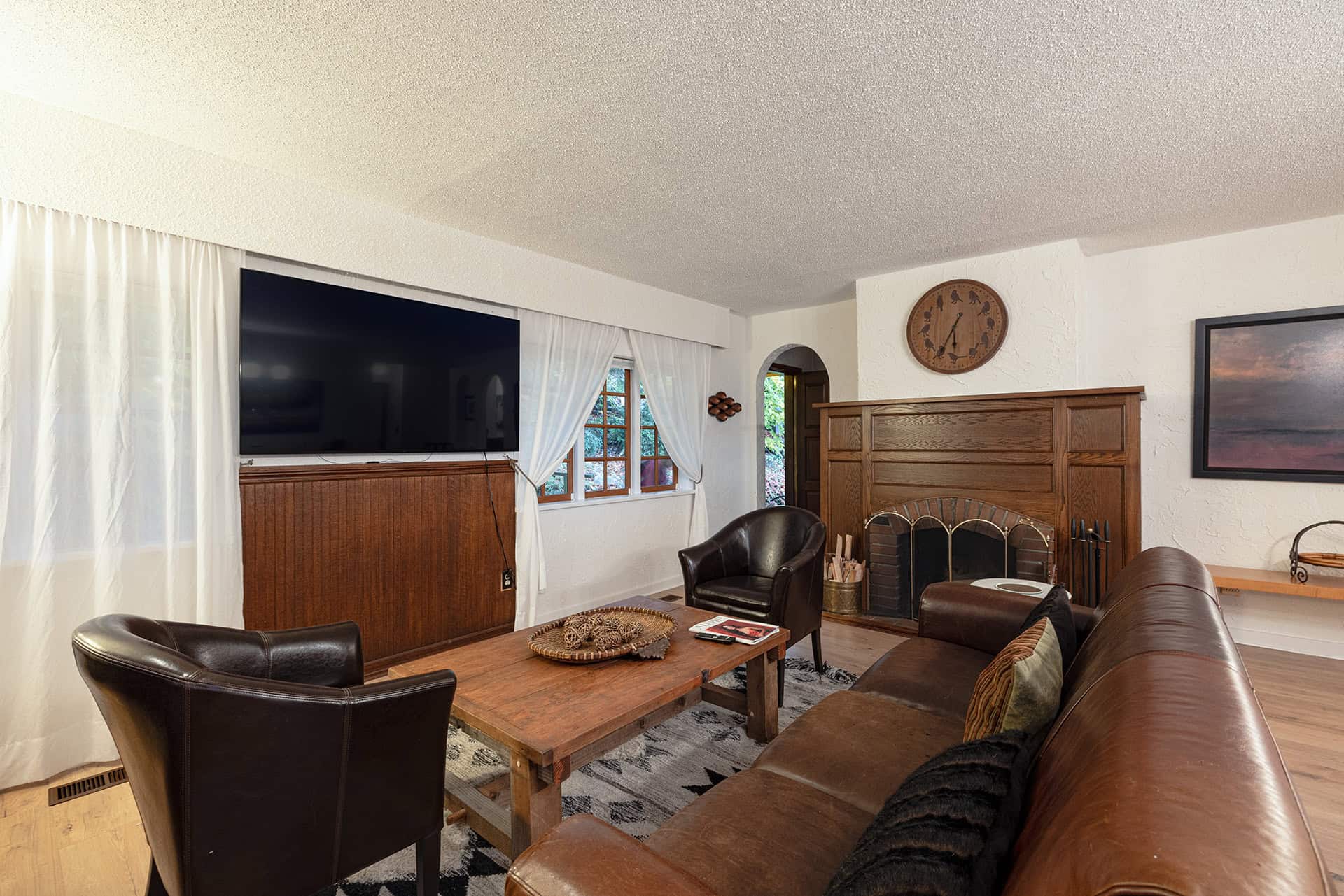 Cozy living room interior with leather sofas, wooden accents, fireplace, and large TV, showcasing a warm and inviting home atmosphere, ideal for families and entertaining guests.