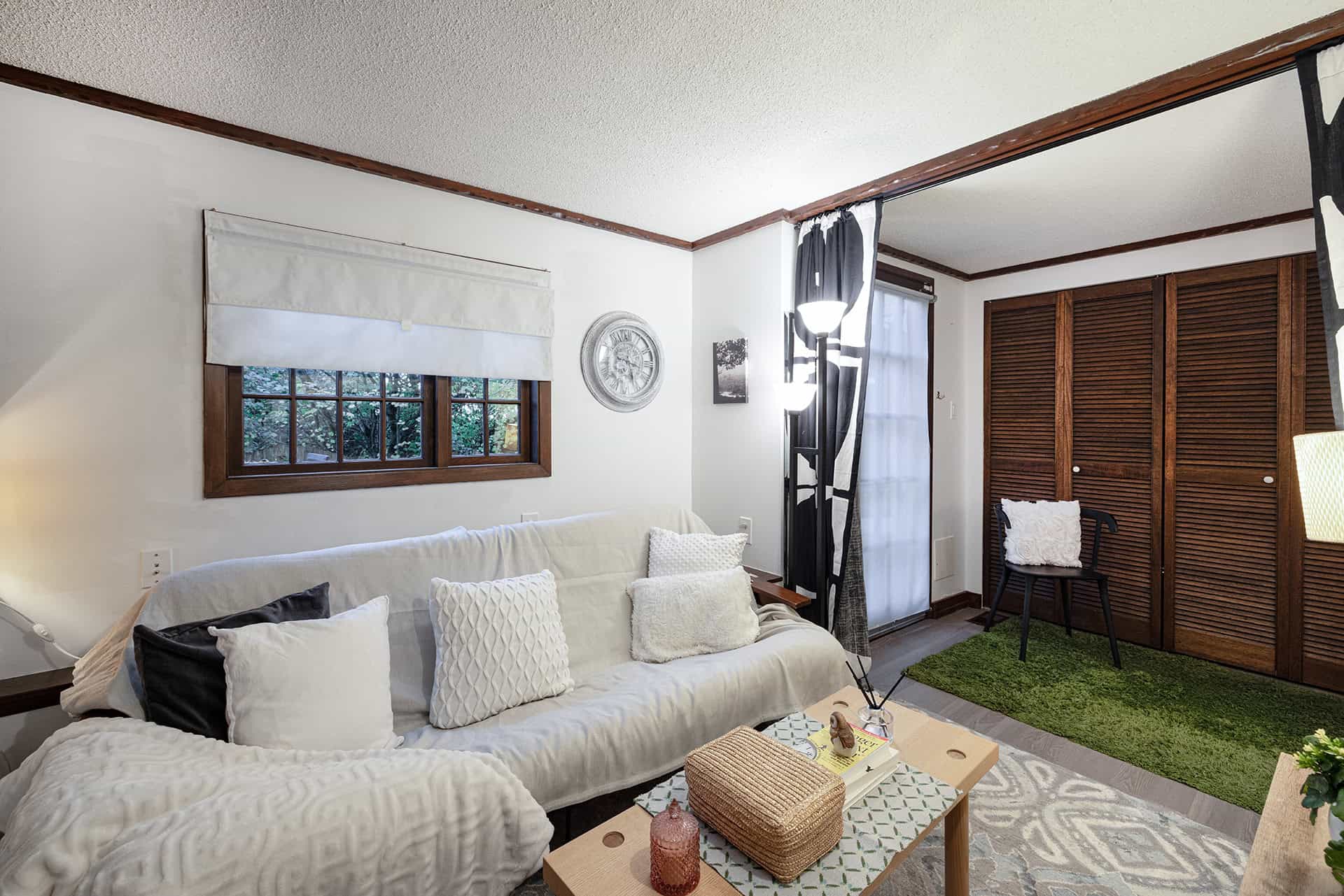 Cozy living room with white sofa, decorative pillows, wooden accents, window with natural light, and stylish interior design by Orca Realty Inc.