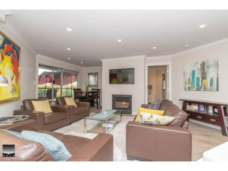 Bright and spacious living room featuring modern furnishings, a cozy fireplace, and large windows with scenic views, perfect for relaxing or entertaining guests.