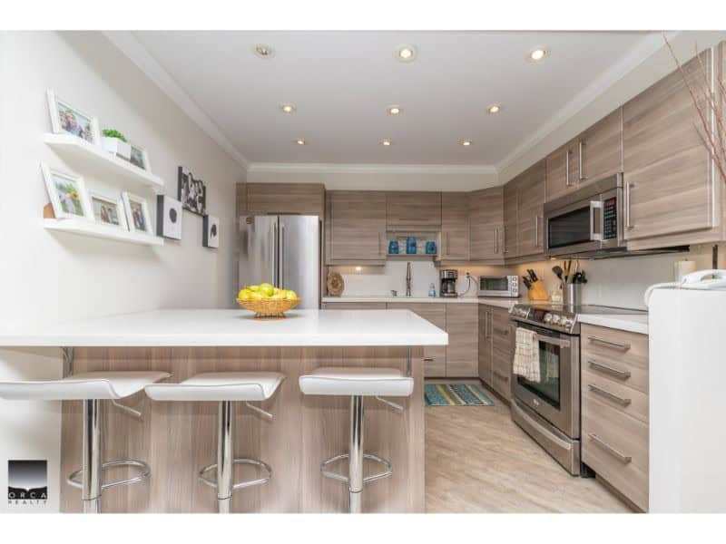 Modern renovated kitchen with stainless steel appliances and neutral wood cabinetry in a contemporary Orca Realty Inc. property.