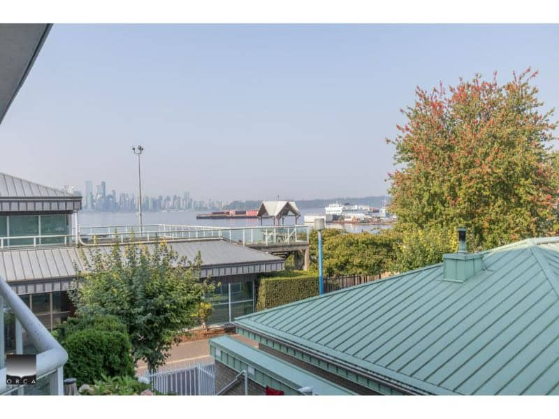 Distinctive water view featuring vibrant fall foliage and modern waterfront structures in Vancouver, BC location with skyline in the distance, ideal for real estate and property sales in Orca Realty Inc.