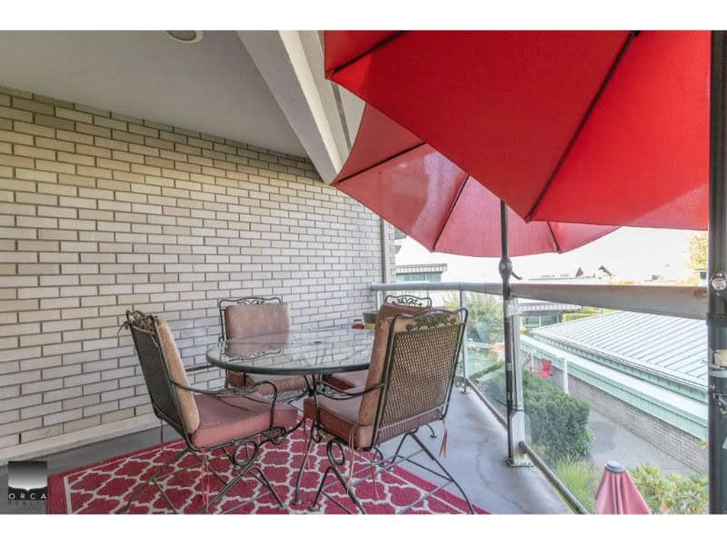 Bright balcony with outdoor dining set, red umbrella, and city view, perfect for relaxing and entertaining in Vancouver real estate.