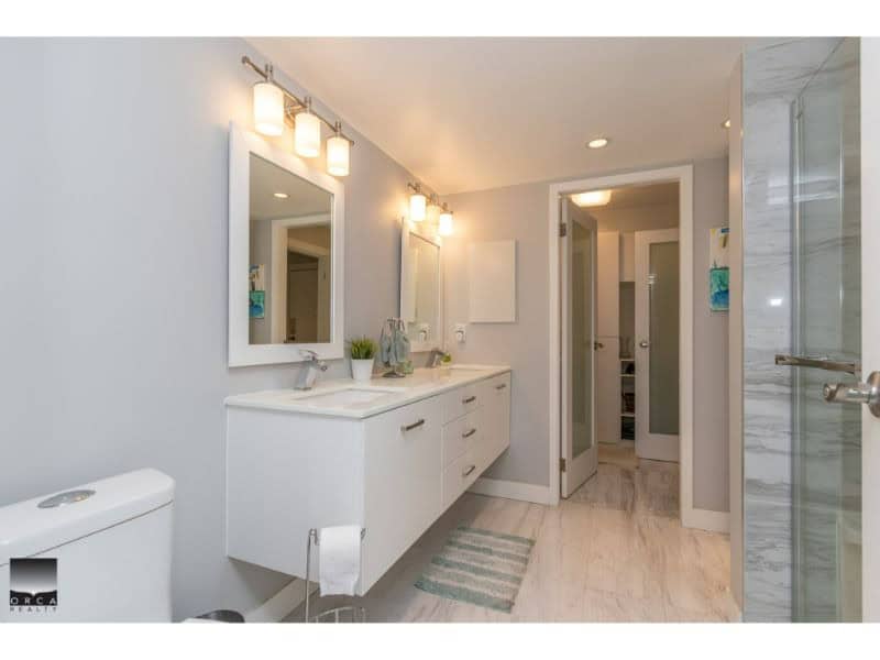 Spacious modern bathroom with double vanity, bright lighting, and elegant fixtures, perfect for comfortable living.