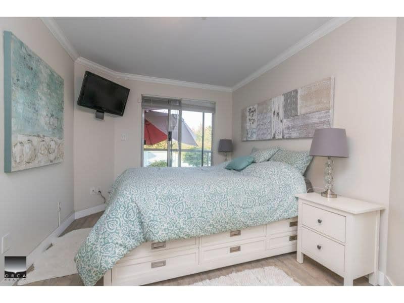 Bright bedroom with a large bed, modern decor, and natural light from sliding glass doors, ideal for Vancouver Island real estate listings.