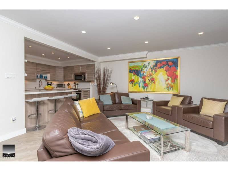 Spacious living room with modern décor, featuring comfortable leather sofas, colorful artwork, and a cozy atmosphere, perfect for relaxing or entertaining guests.