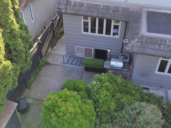 Bright backyard patio with BBQ grill, surrounded by lush greenery and privacy fence, ideal for outdoor entertaining and relaxation.