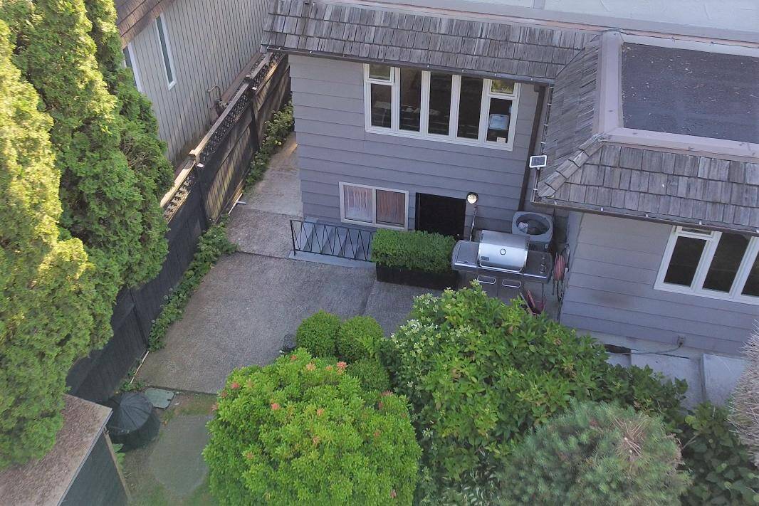 Bright backyard patio with BBQ grill, surrounded by lush greenery and privacy fence, ideal for outdoor entertaining and relaxation.