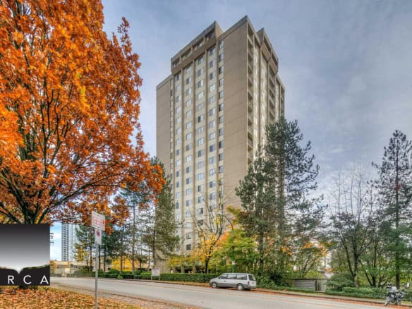 High-rise apartment building with autumn trees and city street in Vancouver, BC, available for real estate services by Orca Realty Inc.