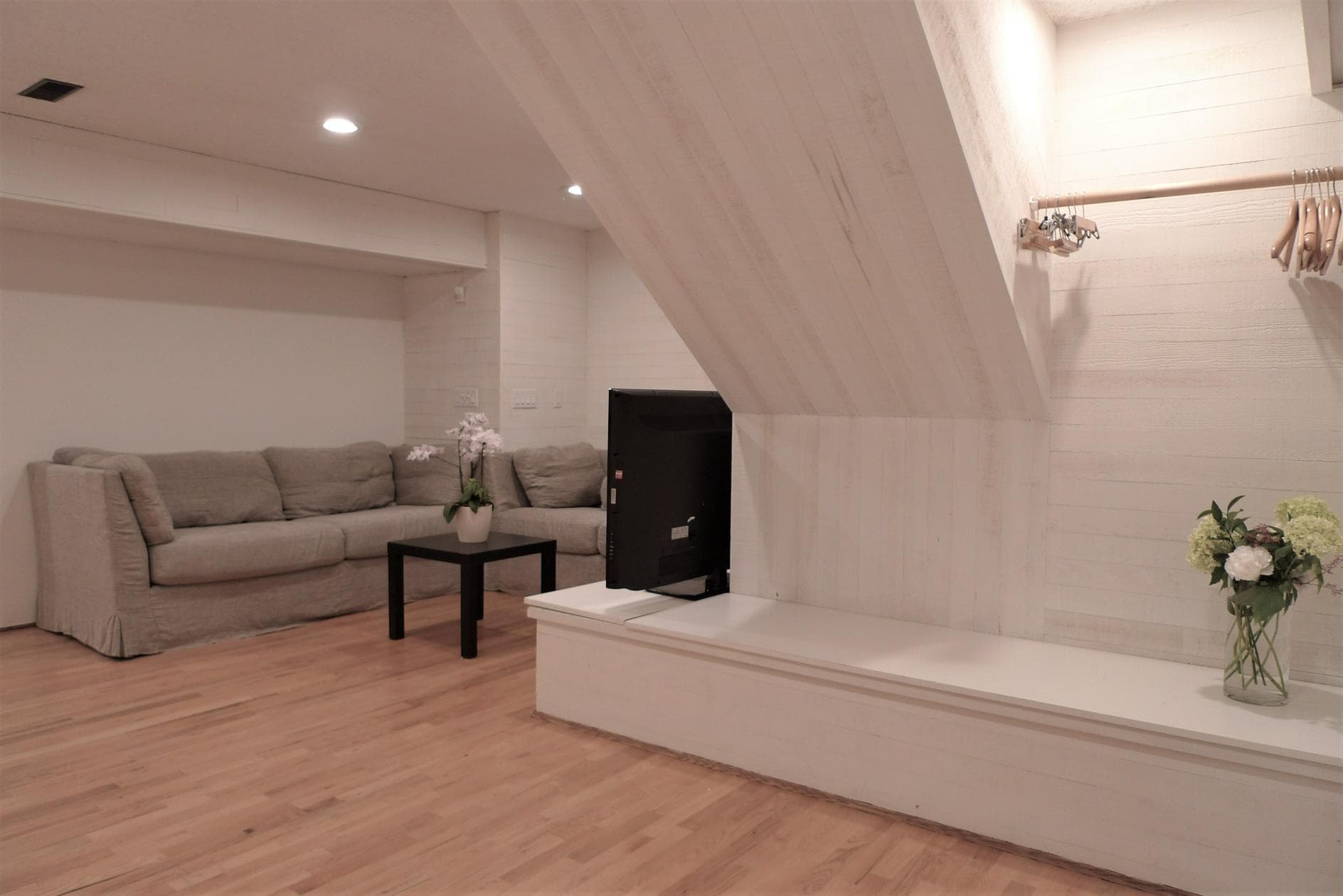 Cozy living room with neutral-toned sofa, wooden flooring, and modern decor, perfect for relaxing or entertaining in a stylish home.