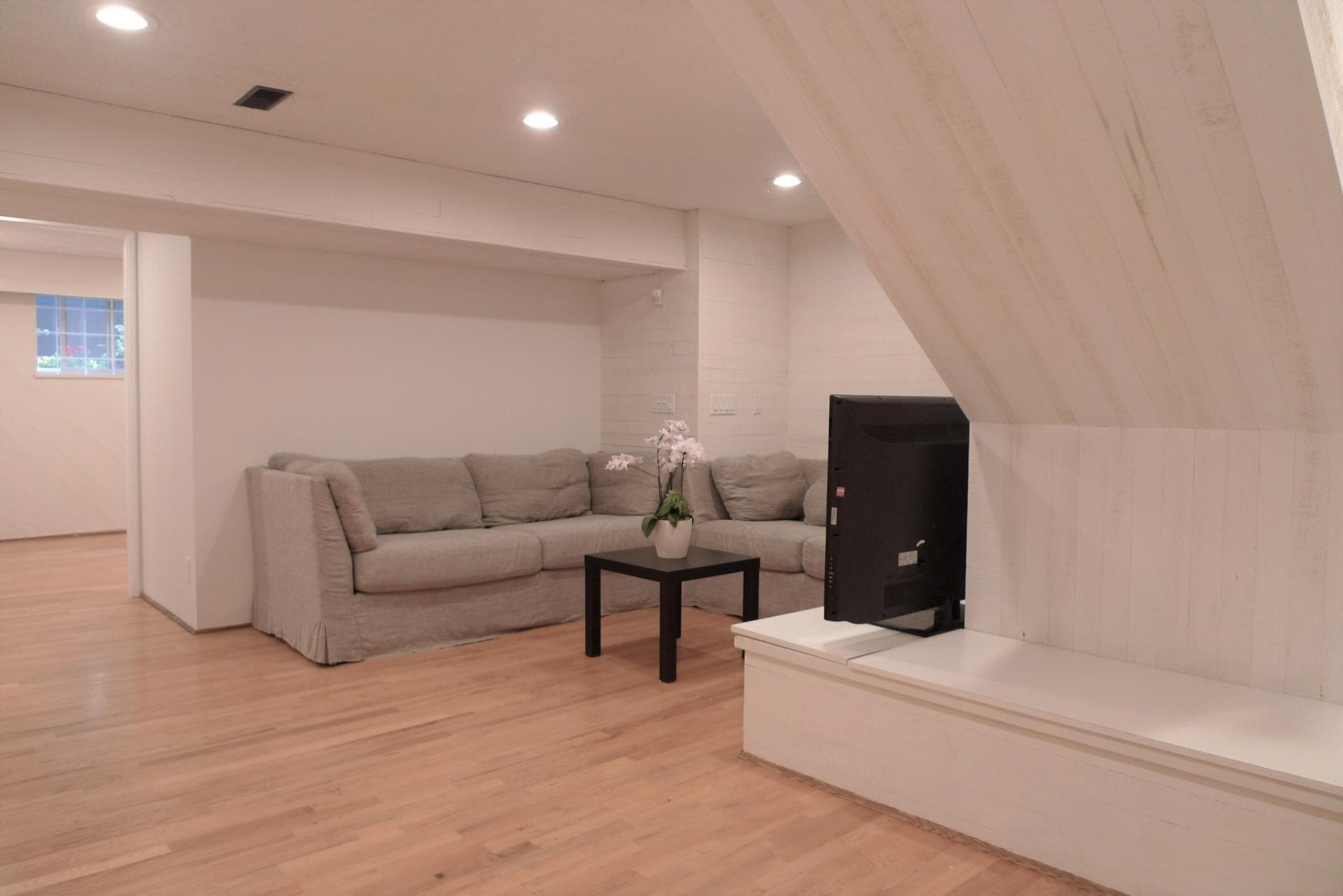 Comfortable living room with a beige sofa, wooden flooring, and modern lighting, showcasing Vancouver Island real estate for sale by Orca Realty Inc.