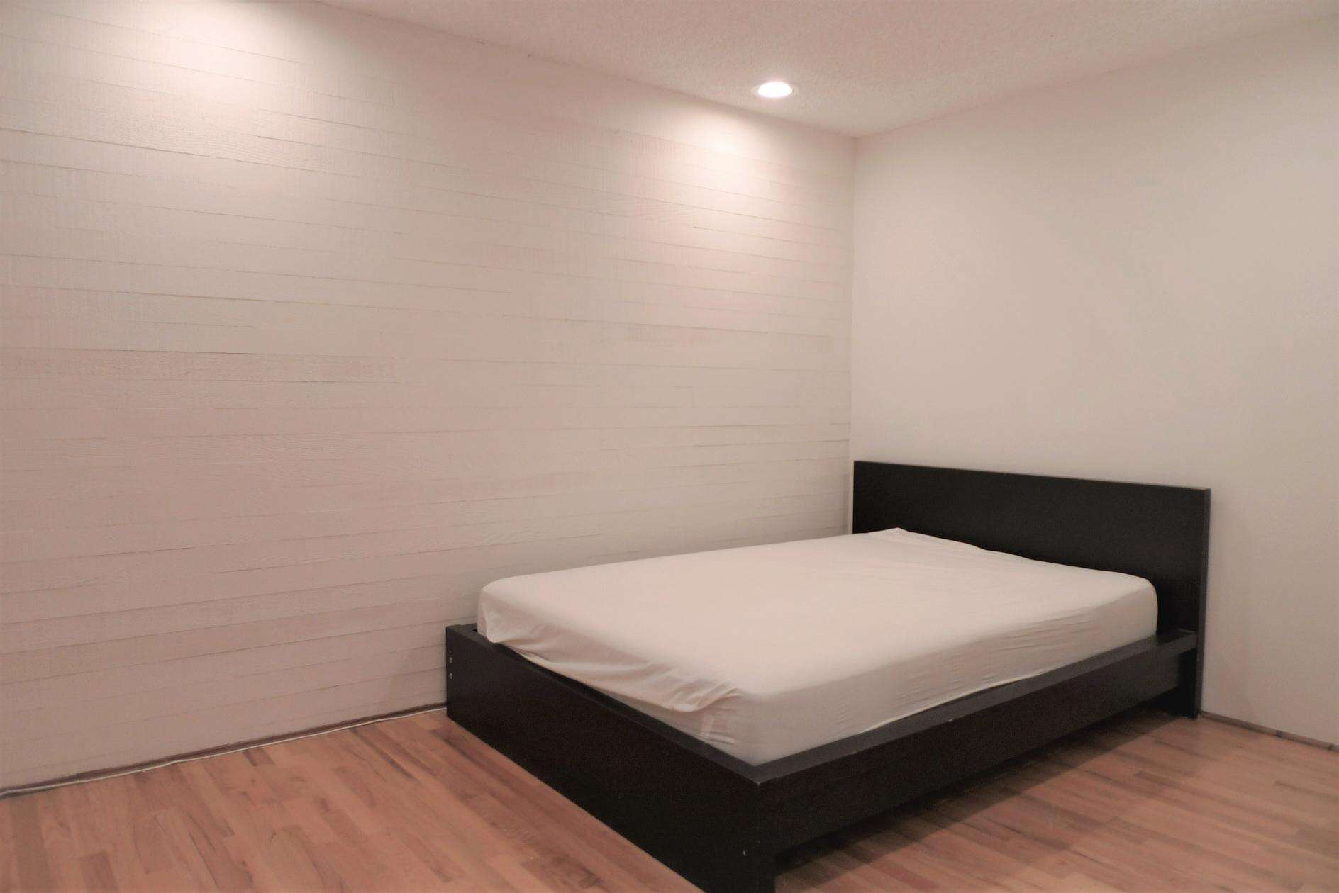 Minimalist bedroom with a black bed frame and white mattress in a modern, well-lit space. Perfect for Vancouver real estate or rental listings.