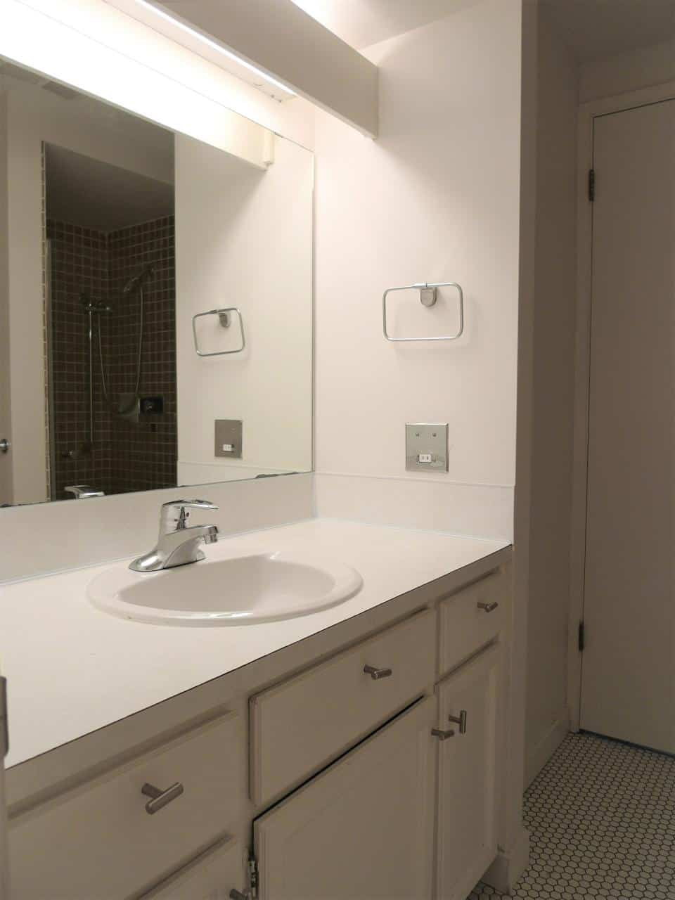 Modern bathroom vanity with white cabinetry, mirror, and contemporary fixtures in a clean, updated interior space.