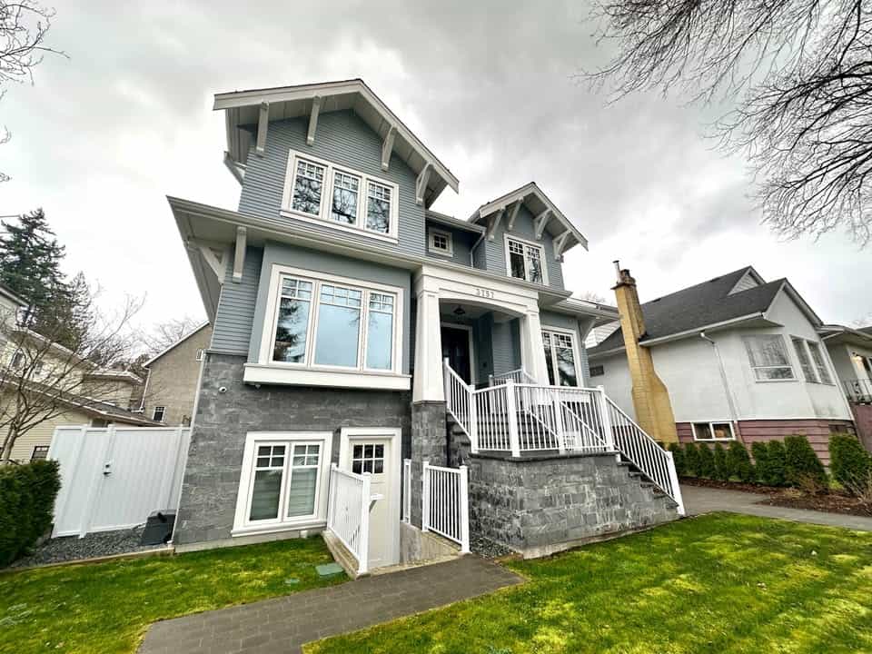 Modern family home with grey siding and stone accents, featuring a welcoming front porch, large windows, and a landscaped lawn in a desirable neighbourhood.