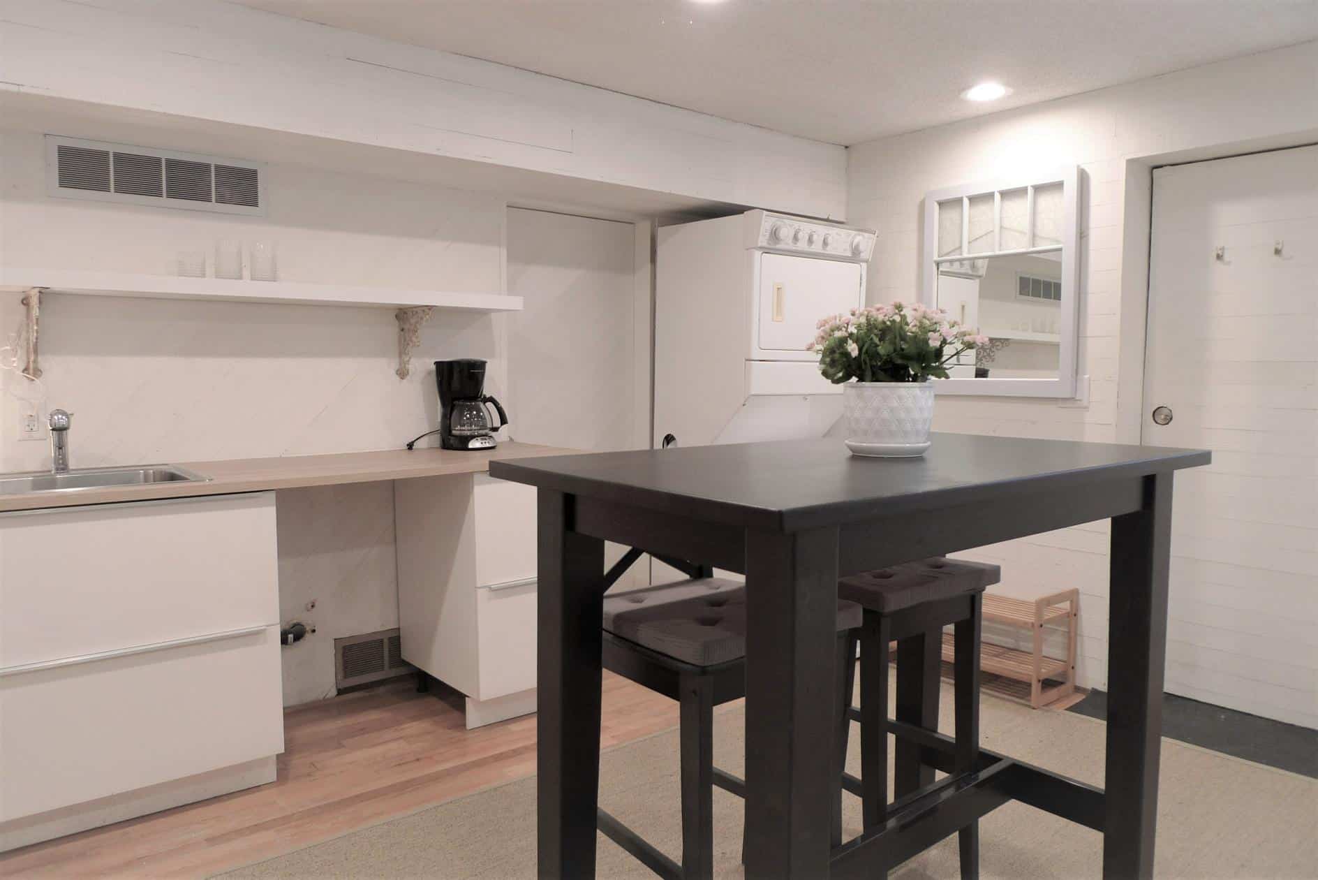 Cozy kitchen with white cabinets, a small dining table, and a laundry area featuring a stacked washer and dryer, offering functional space and modern amenities in a compact home.