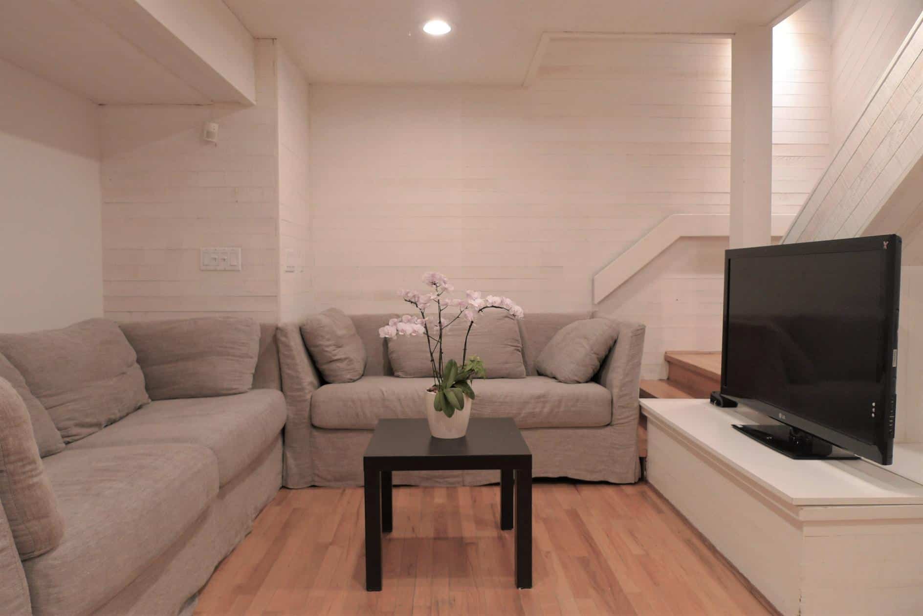 Cozy living room with neutral-toned sofa, modern decor, and flat-screen TV, ideal for relaxing in a Vancouver or BC home offered by Orca Realty Inc.