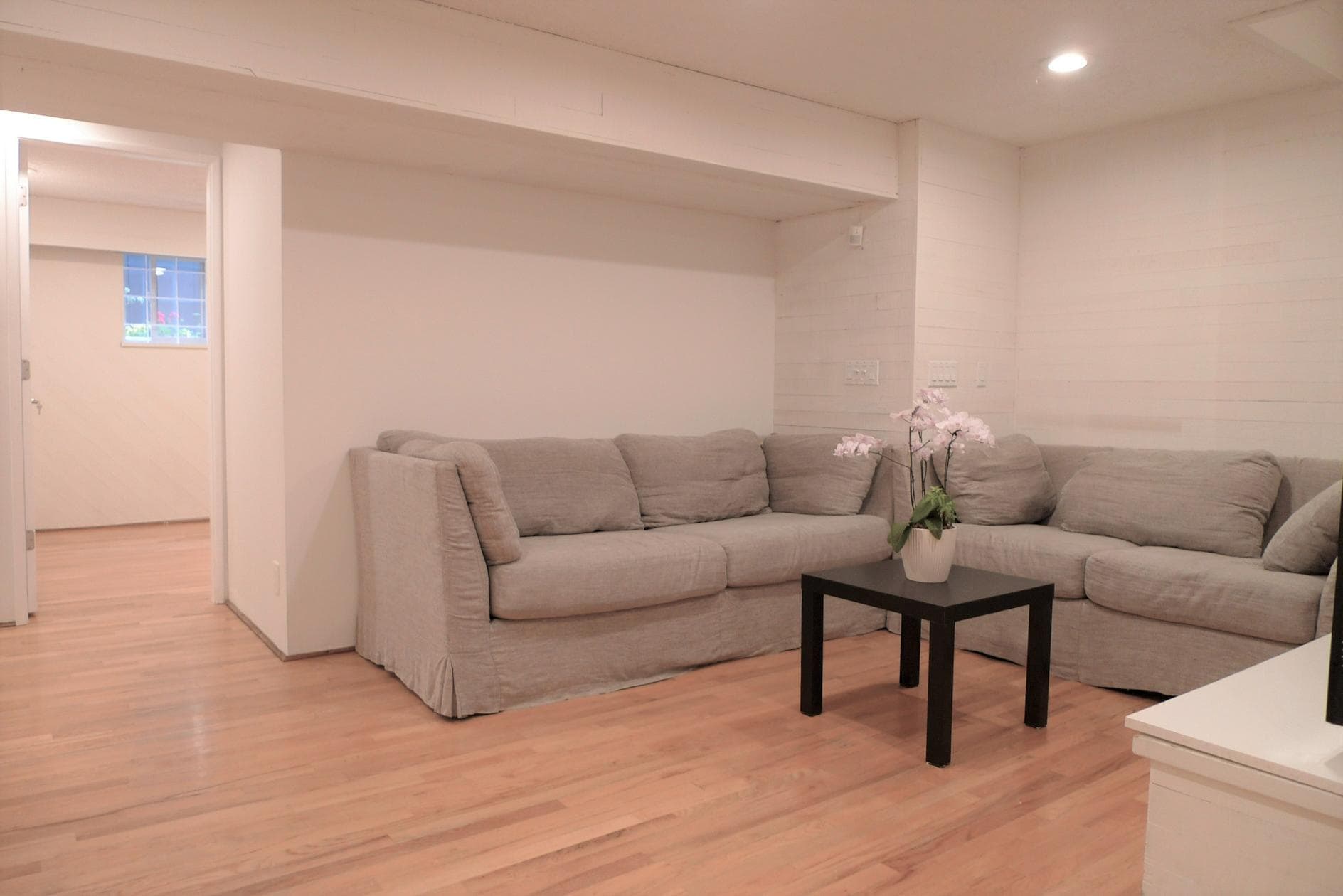 Cozy grey sectional sofa in a modern living room with hardwood floors, minimalist decor, and soft lighting, ideal for comfortable family gatherings and relaxing at home.