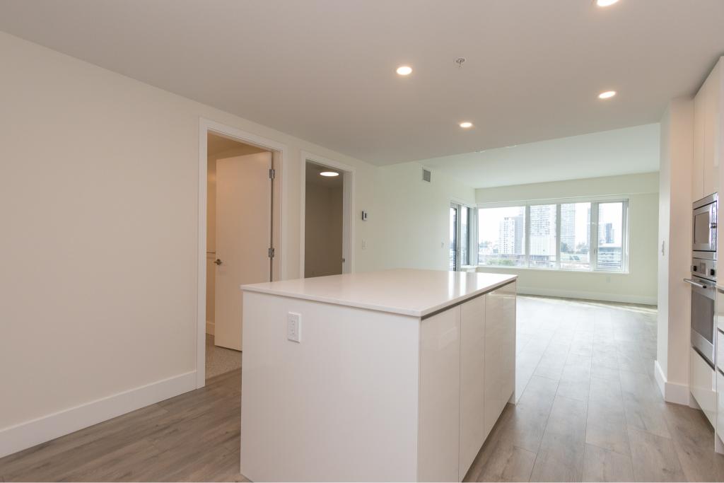 Bright modern open-concept kitchen and living space in Vancouver condo, featuring large windows, sleek white cabinetry, and contemporary design, ideal for urban living.