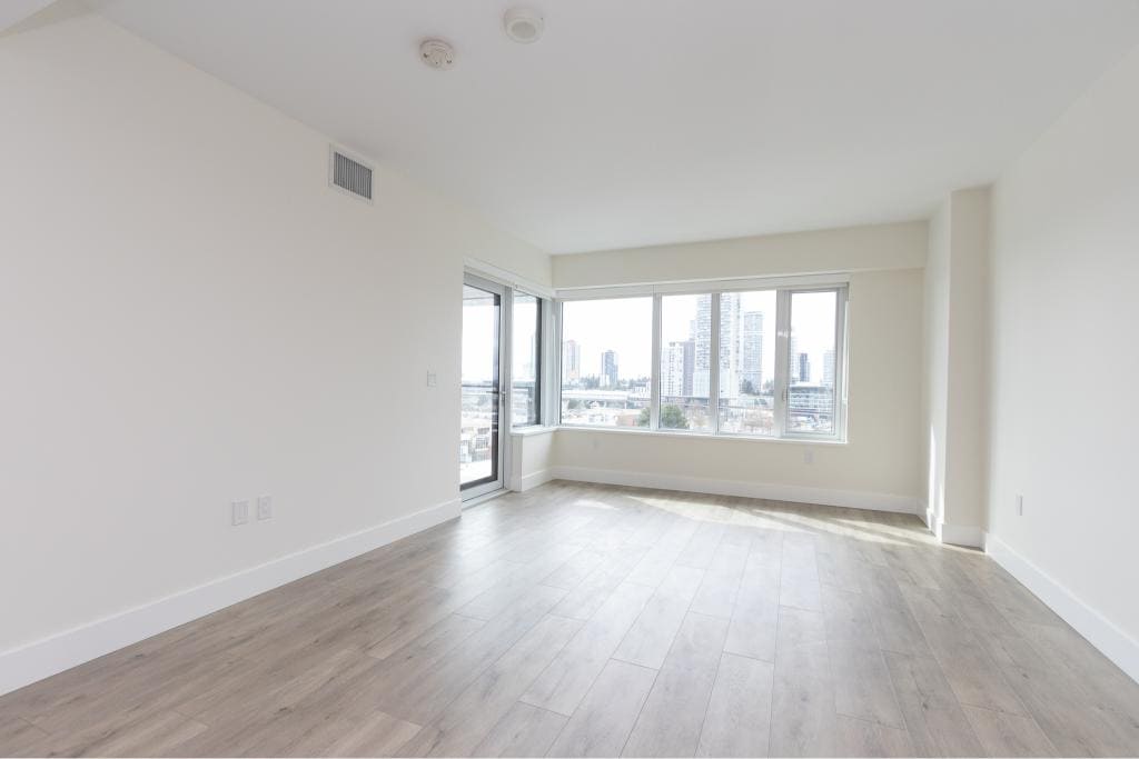 Spacious modern living room with large windows showcasing city views, ideal for Vancouver real estate and condo buyers.