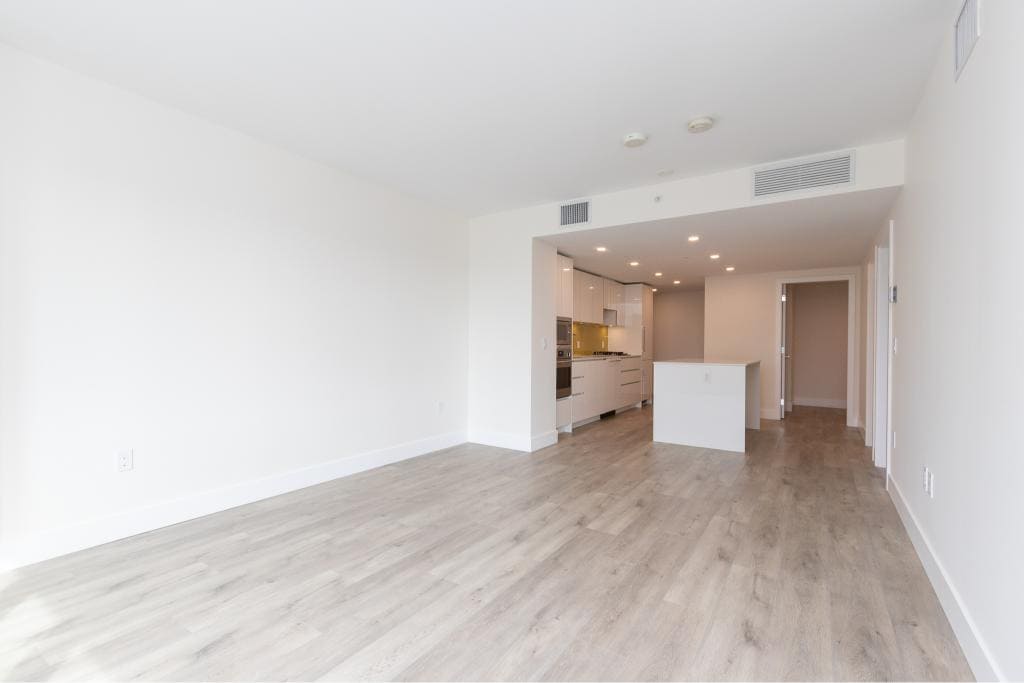 Bright open-concept living space with modern kitchen, ideal for Vancouver real estate market, featuring sleek white cabinetry and hardwood flooring.