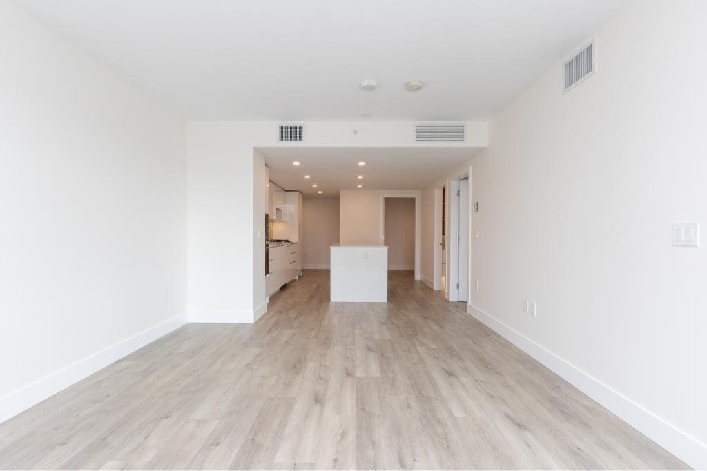 Modern open-concept apartment interior with white walls, light wood flooring, and a minimalist kitchen setup for contemporary urban living.