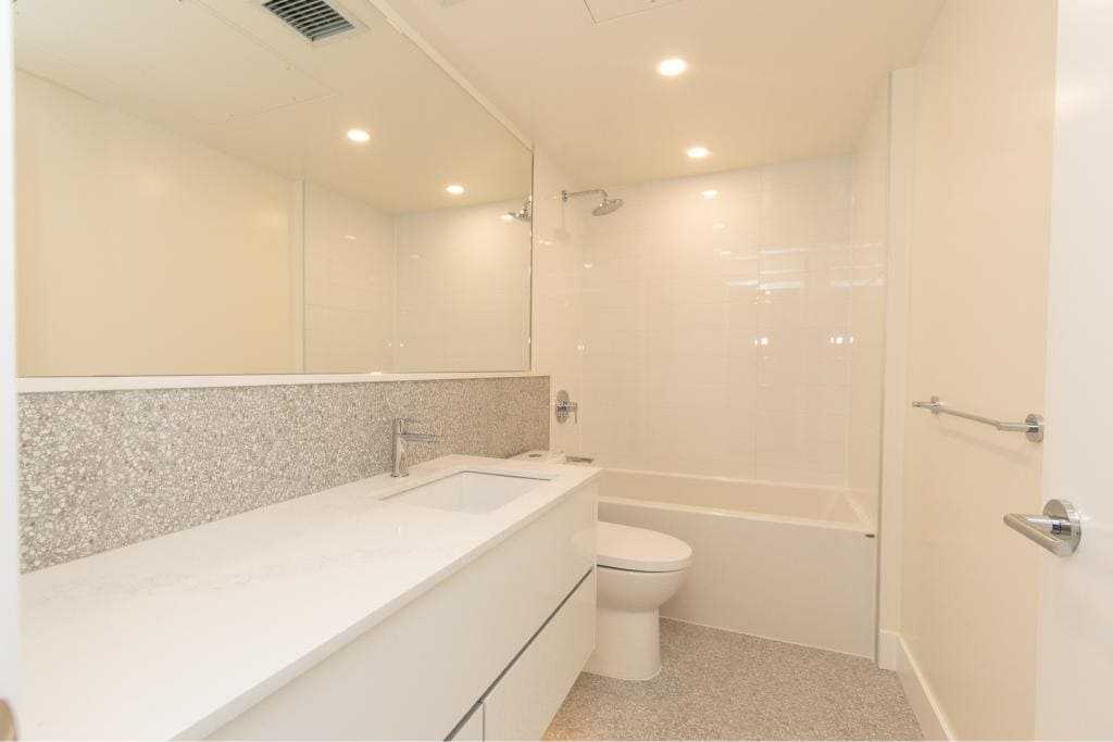 Modern bathroom interior with white vanity, sink, and bathtub in a contemporary condo. Ideal for clients seeking stylish, functional real estate in Vancouver.
