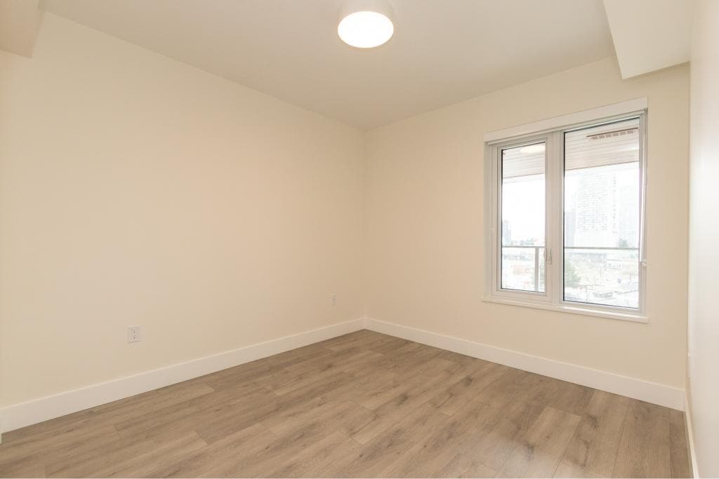 Bright empty room with large window and modern flooring in a condo or apartment, ideal for Vancouver real estate listings.
