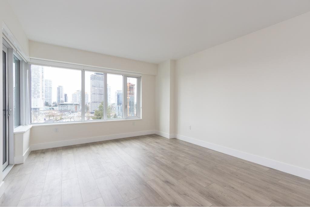 Bright unfurnished living room in downtown Vancouver with panoramic city views, large windows, modern flooring, and ample natural light, ideal for contemporary condo living.