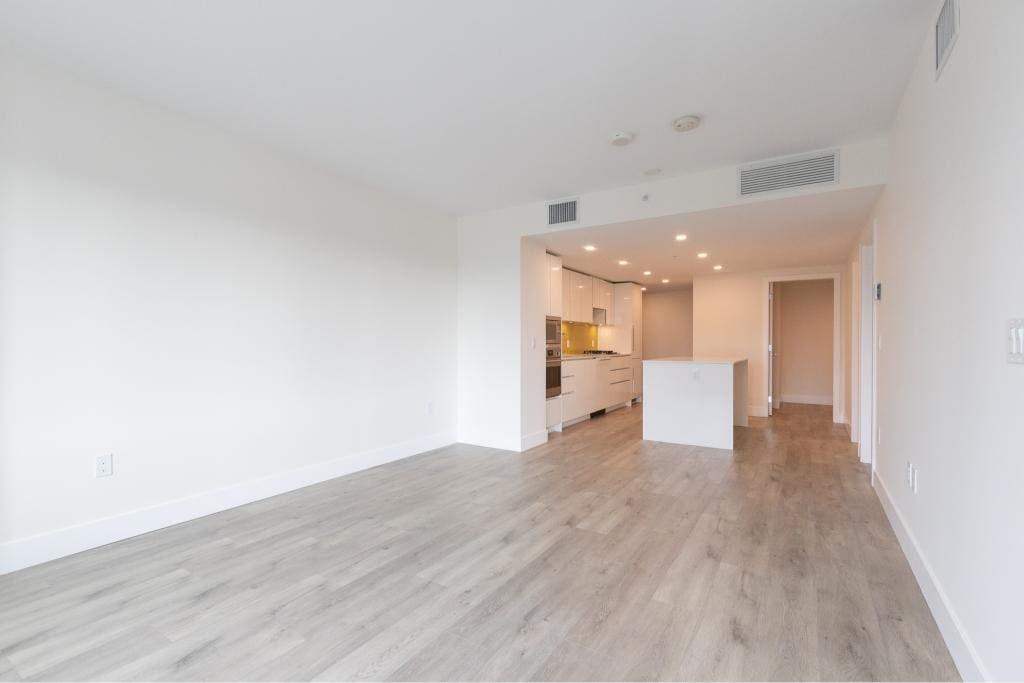 Spacious modern living room with open-concept kitchen, bright lighting, neutral decor, ideal for Vancouver real estate buyers.