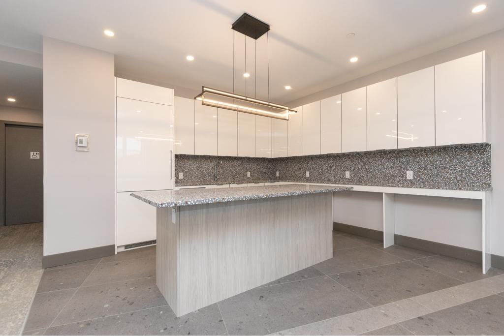 Modern kitchen with white cabinets, granite countertops, and sleek lighting, perfect for Vancouver real estate investments and homebuyers from Orca Realty Inc.