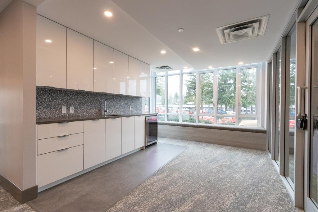 Modern commercial kitchen and lounge area with large windows, ideal for real estate offices or community spaces in Vancouver Island.