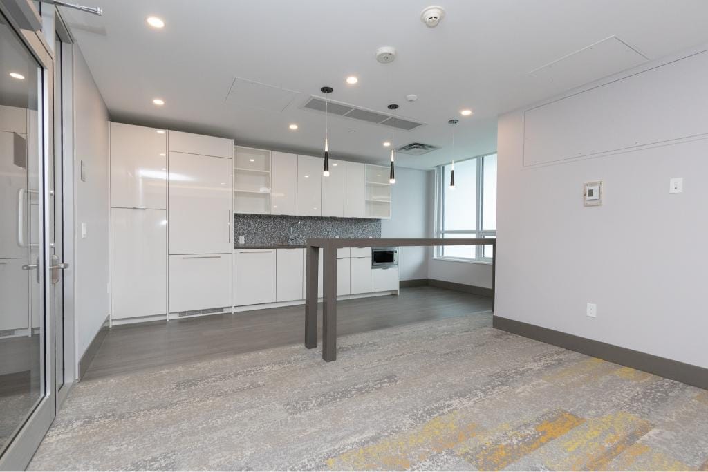 Modern minimalist kitchen interior with sleek white cabinetry, ample natural light, and contemporary pendant lighting at Orca Realty Inc. in Vancouver.