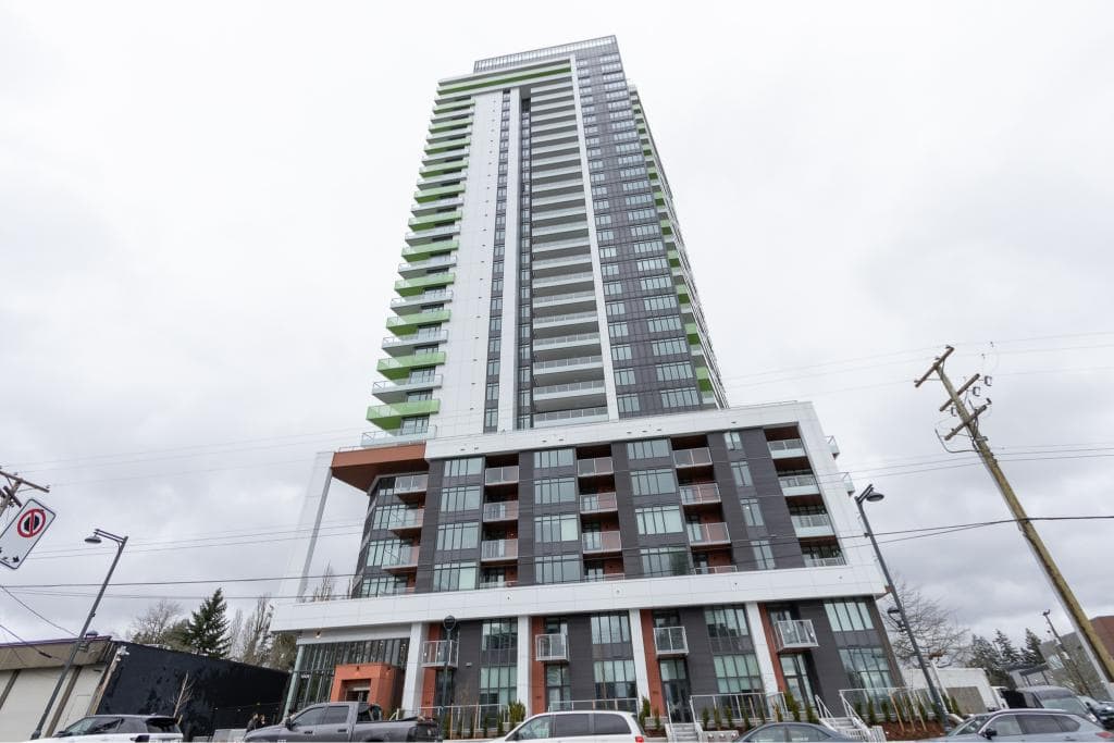 Modern high-rise condominium building in Vancouver, BC, featuring contemporary architecture with glass balconies and green accent elements, perfect for luxury urban living.