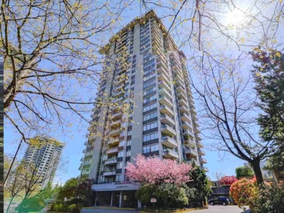 Contemporary high-rise apartment building with balconies, surrounded by spring blossoms and mature trees, in a desirable Vancouver neighbourhood.