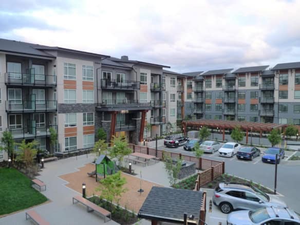 Modern multi-story apartment complex with landscaped courtyard and parking, available through Orca Realty Inc. in Vancouver, BC. Perfect for residential living with amenities and scenic views.