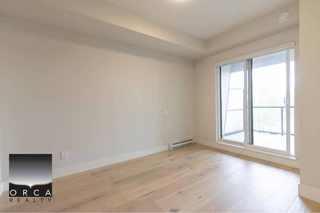 Bright, modern living room with large sliding glass doors leading to a balcony, featuring hardwood flooring and neutral wall colors, ideal for Toronto condo living.