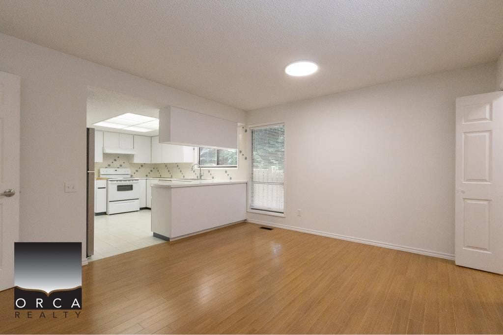 Bright and spacious living room in a Vancouver home with open kitchen, laminate flooring, large windows, ideal for family gatherings and entertaining.