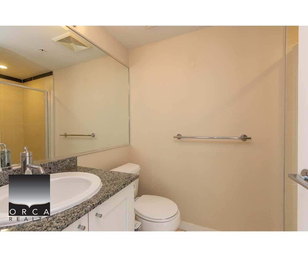 Modern bathroom interior with granite countertop, white sink, mirror, and towel bars, showcasing updated home features from Orca Realty Inc. in Canadian real estate market.
