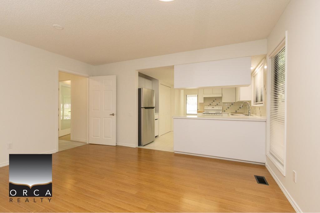Bright open-concept kitchen and living space in a modern home listed by Orca Realty Inc. in Victoria, BC. Custom cabinetry, stainless steel appliances, and hardwood floors highlight stylish, functional design.