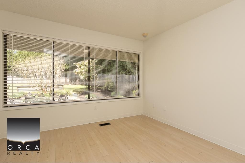 Bright empty room with large front window showcasing a landscaped backyard, ideal for Vancouver real estate listings.