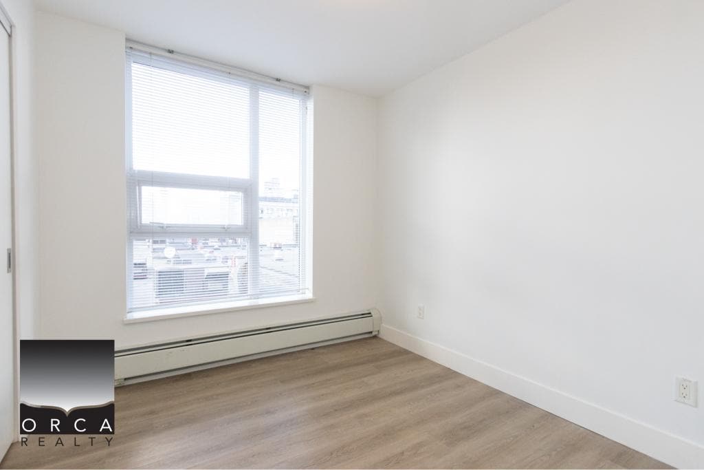 Bright, empty room in Vancouver apartment with large window and natural light, ideal for residential real estate listings in Vancouver.