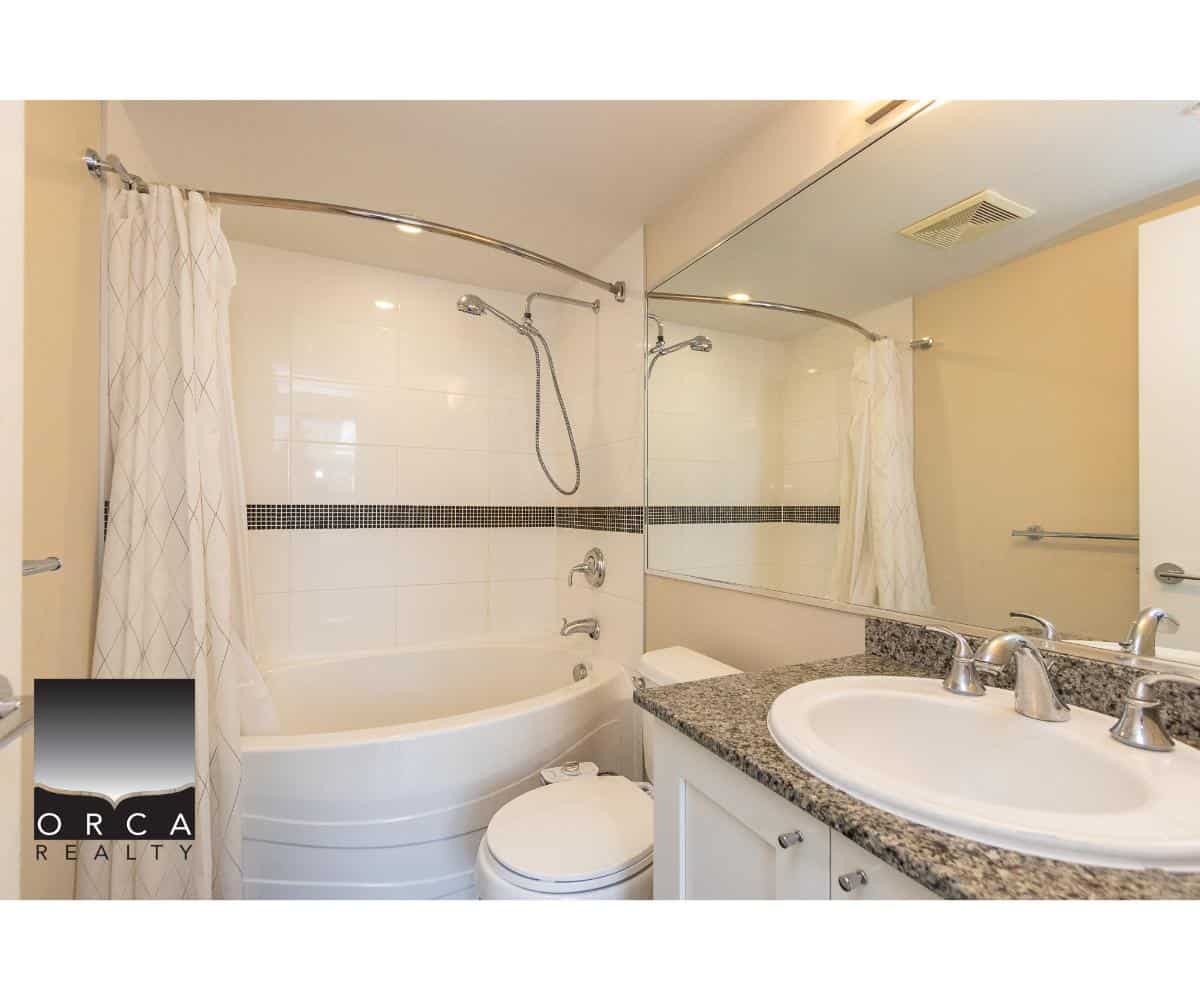 Modern bathroom with shower and bathtub, granite countertop sink, and mirror - ideal for Vancouver Island real estate.